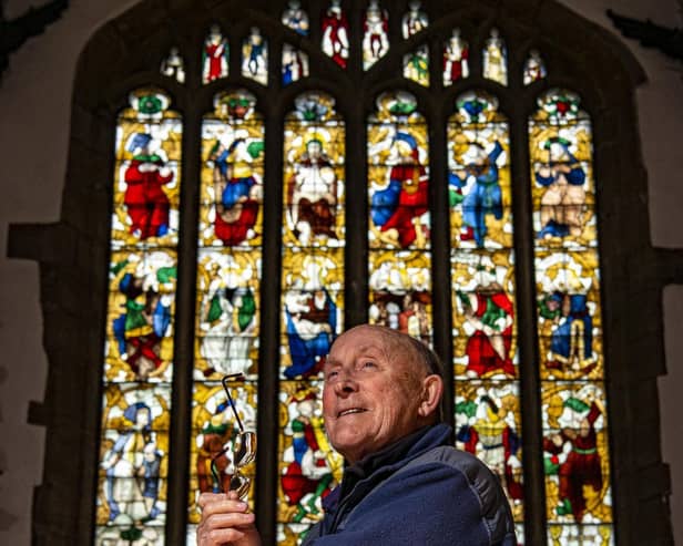 Brian Pearson with the restored medieval stained glass panels on show in the church.