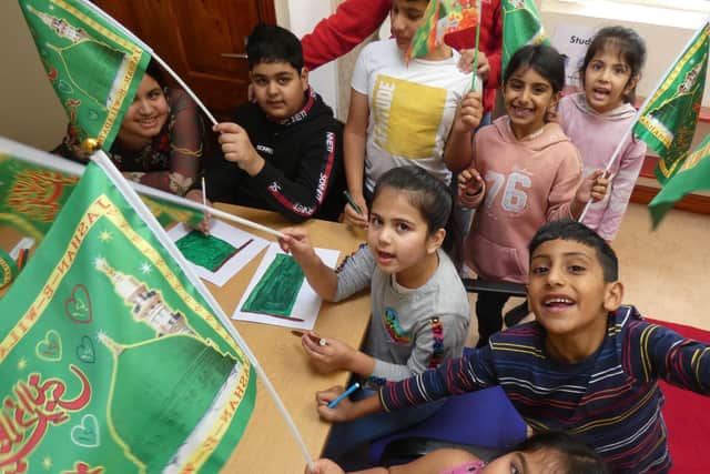 A small group of Muslim children celebrating Prophet Mohammad's birthday by waving green Sufi-Muslim flags symbolising love for nature and the environment. Photo taken at an Eid-Milad Playscheme event held at the Faizan-E-Madina Jamia Mosque on Dewsbury Moor in October 2020.
