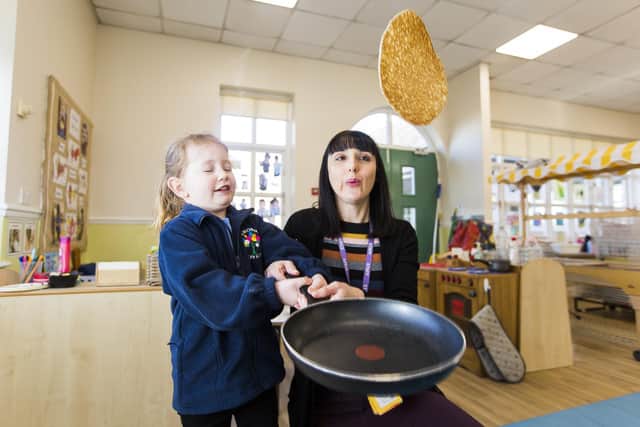 Nursery teacher Francesca Brant and Cassidy Hanson, four, toss a pancake at Heckmondwike Primary School