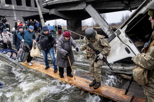 Residents of Irpin flee heavy fighting via a destroyed bridge as Russian forces entered the city. Photo: Getty Images
