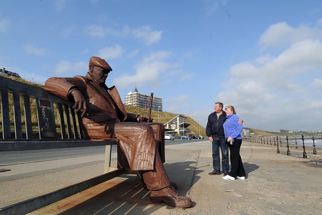 Freddie Gilroy sits on a bench facing the North Sea in Scarborough’s North Bay. He is wrapped up in an overcoat, a cloth cap pulled down, a walking stick in one hand and the other arm draped across the bench.
He is a giant steel sculpture created by Ray Lonsdale. Freddie Gilroy was a 23-year old miner and one of the first soldier to relieve the Bergen-Belsen concentration camp at the end of the Second World War.