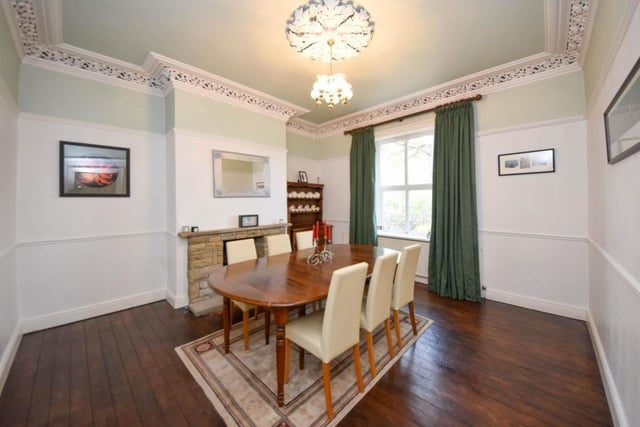 This room, with wooden floor and stone fireplace, has room for a large dining table and chairs.