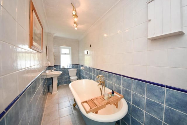 A free standing bath with claw feet is a feature of the tiled bathroom.