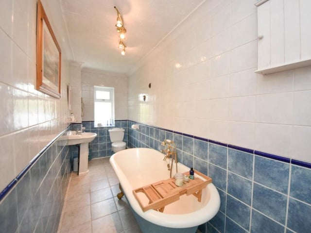 A free standing bath with claw feet is a feature of the tiled bathroom.