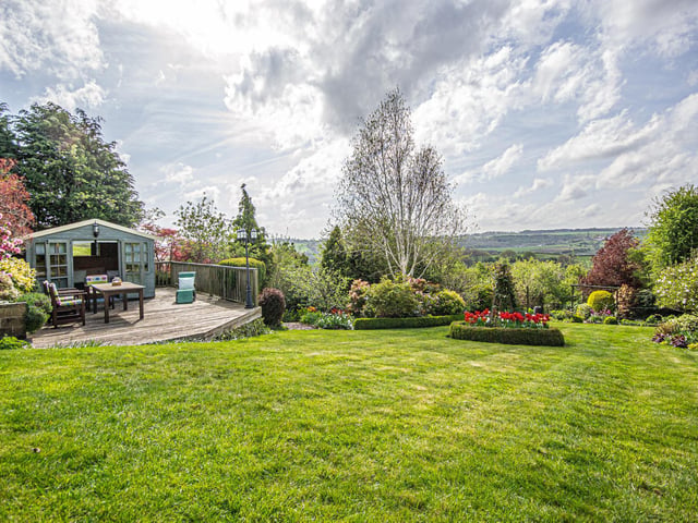 A lawn, decking and summer house, with the view stretching beyond.