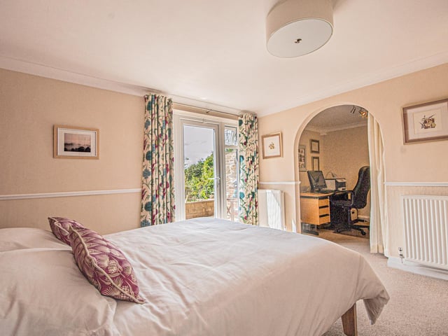 This bedroom has a second space, seen through the archway, that currently serves as a home office but could be a dressing room if preferred.