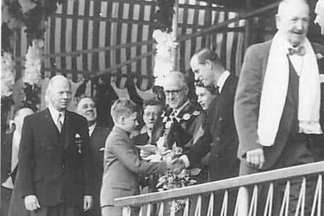 A young John Boland-Lee shakes the hand of Her Majesty and the Duke of Edinburgh