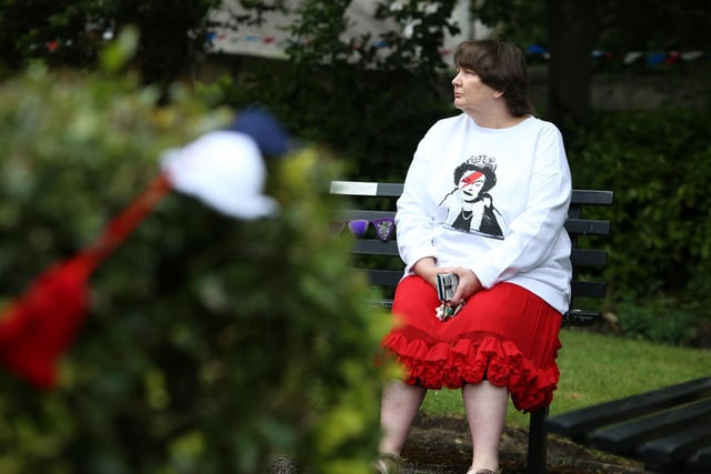 A volunteer from The Friends of Cleckheaton Library wearing a jumper with The Queen on, sits on a bench on Platinum Jubilee Weekend