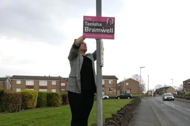 Election candidate Tanisha Bramwell affixes a sign as part of her campaign. Some signs have been taken down, with one set on fire.