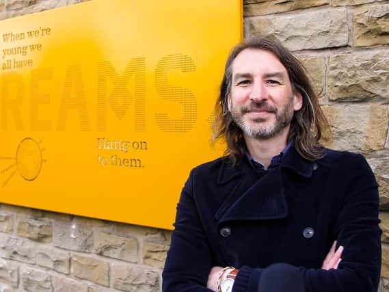 Artist Adrian Riley with the 'Dreams' art panel installed on the side of Dewsbury bus station