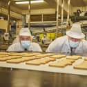 Prime Minister Boris Johnson and Ryan Stephenson, Conservative candidate in the Batley and Spen by-election, take a closer look at some of the biscuits being made at the Fox's factory in Batley. Photo by Joel Anderson