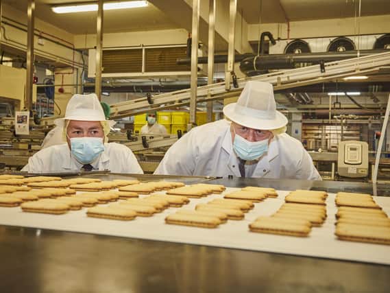 Prime Minister Boris Johnson and Ryan Stephenson, Conservative candidate in the Batley and Spen by-election, take a closer look at some of the biscuits being made at the Fox's factory in Batley. Photo by Joel Anderson