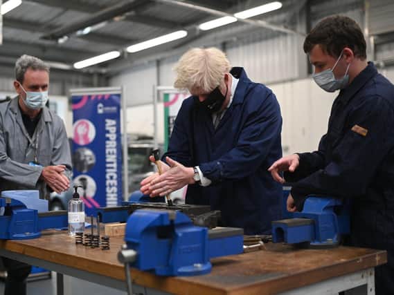 VISIT: Prime Minister Boris Johnson assists in an engine repair at the automotive shop at Kirklees College. Photo: Getty Images