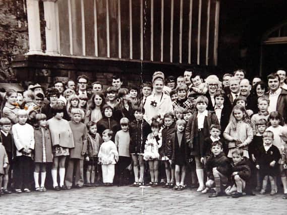 OUTING: A happy smiling group of children with their parents and patrons of the Station Hotel, Dewsbury, outside Wellington Road Station before setting off for a trip to the seaside in the 1970s. In the middle is landlady Beth Elliott with her smart beehive hairstyle. She and her husband, Ernest, were popular licensees of the Station in its heyday.