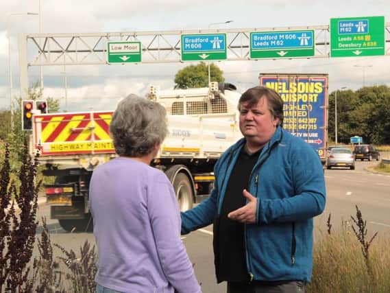 Coun John Lawson, leader of the Liberal Democrats on Kirklees Council, with ward colleague Coun Kath Pinnock at junction 26 of the M62 at Chain Bar as traffic passes in the background