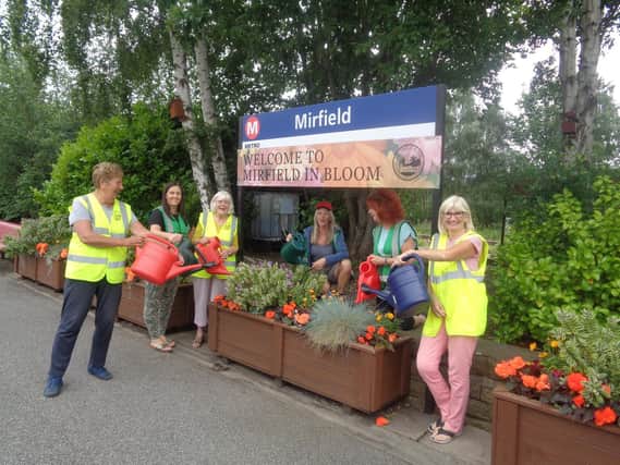 Volunteers watering plants at Mirfield train station