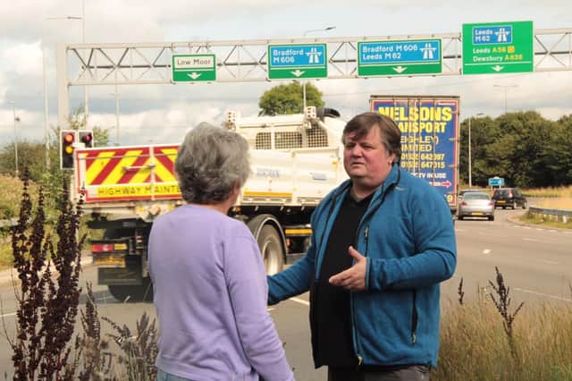 Coun John Lawson, leader of the Liberal Democrats on Kirklees Council, with ward colleague Coun Kath Pinnock at junction 26 of the M62 at Chain Bar as traffic passes in the background
