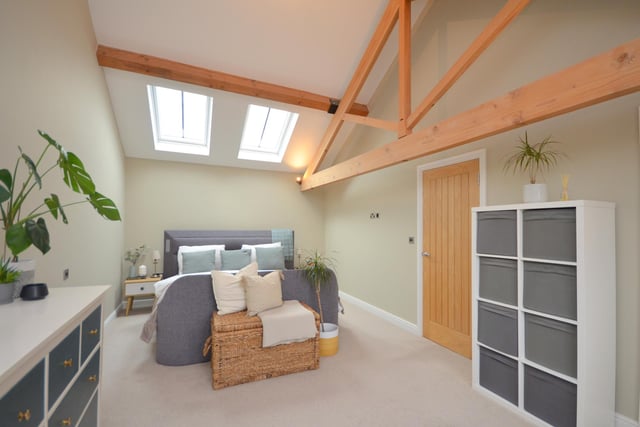 A bedroom with beamed and vaulted ceiling, and skylight windows.