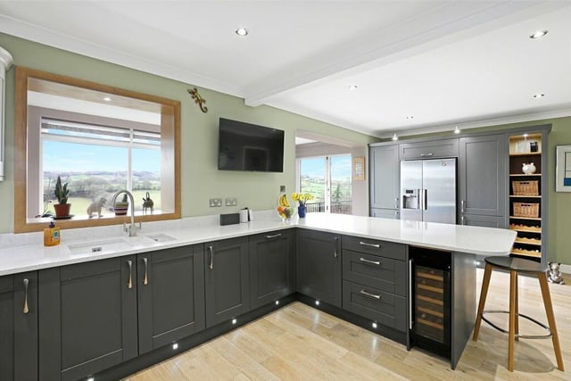 The kitchen also features a built-in induction hob with extractor hood, a double oven, an integrated dishwasher, space for a fridge freezer, a wine cooler, downlighting to the ceiling and a central heating radiator.