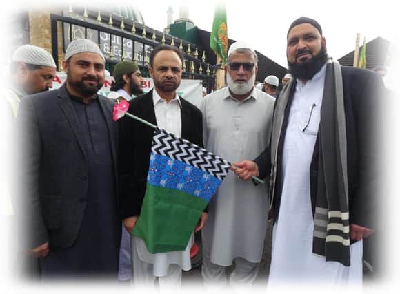 Men holding a green and blue Sufi-Muslim flag of peace during the procession in Dewsbury