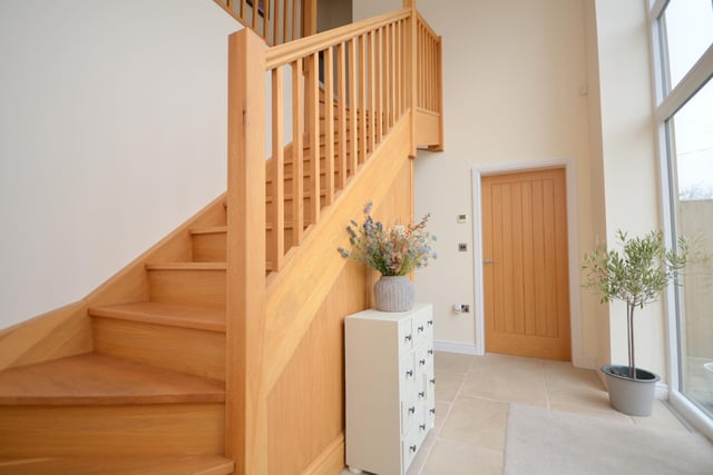 The bright hallway has oak doors and staircase, with built-in storage underneath.