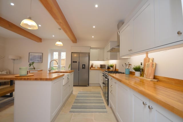 A modern, fitted kitchen with central island is open plan to a dining area, with doors leading outside.