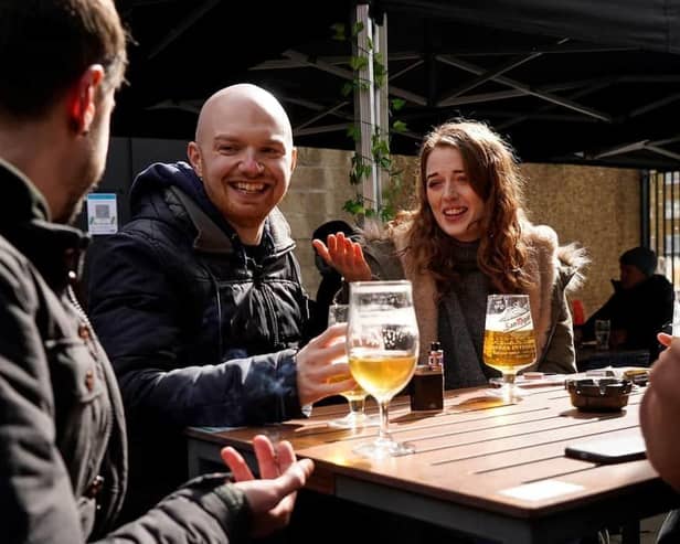 Customers at an outside table as they enjoy food and drinks. (Photo by NIKLAS HALLE'N/AFP via Getty Images).