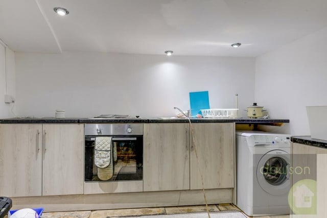 A section of the kitchen that has a stone flagged floor, with fitted units and an electric oven, grill, and four-ring hob.