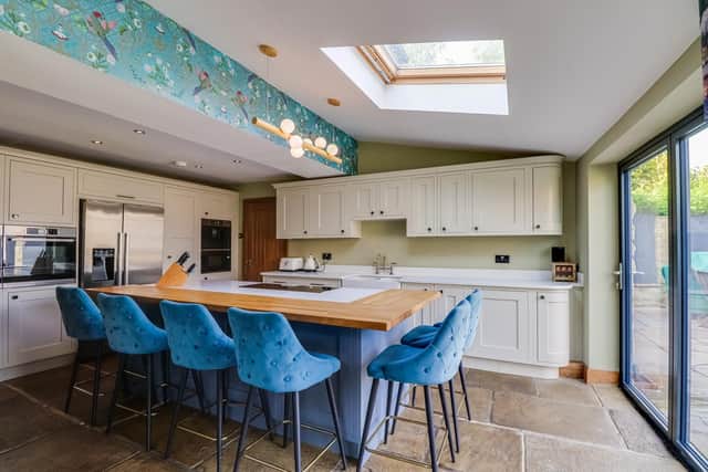 The large central island with seating is a feature of the bespoke kitchen, with fitted units and integrated appliances.