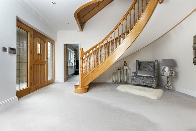 A bespoke curved staircase is a dominant feature in the spacious hallway.