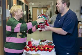 Susan Crossland donating knitted hats to ward manager Callum Douglass at the Neonatal Unit at Pinderfields hospital in Wakefield.