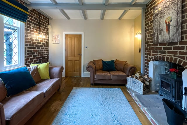 The lounge has a dual fuel log burner within a feature firepace, with beams to the ceiling and exposed brick walls.