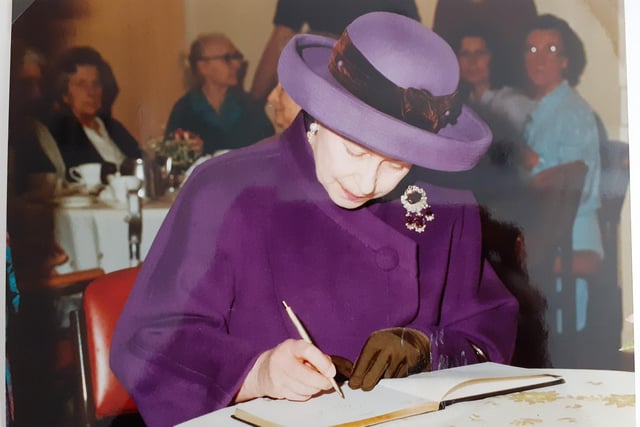 Her Majesty Queen Elizabeth II signing the visitor book at Claremont House.