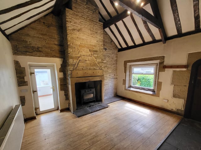 This character dining hall has a vaulted ceiling, an exposed stone wall, and a stone fireplace housing a wood burner.