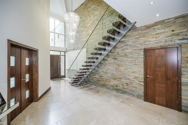 A spacious hallway with stainless steel staircase and glass balustrade.