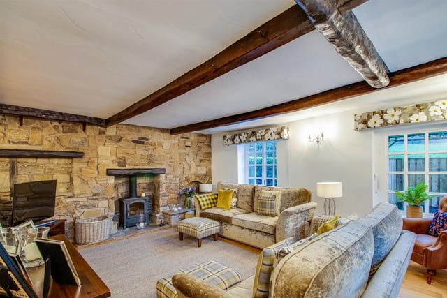 The rustic style sitting room with feature exposed stone wall also has large windows allowing natural light to flood in.