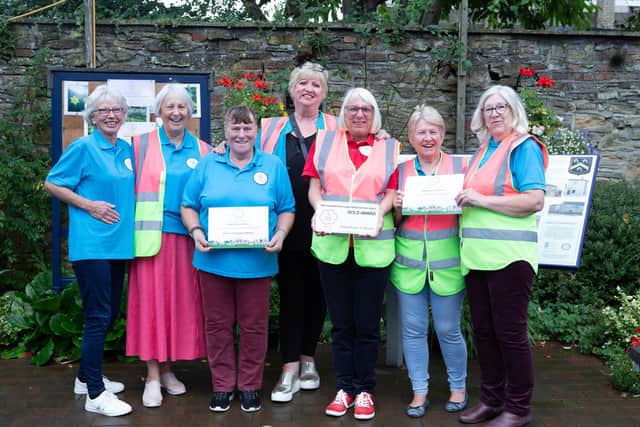 Roberttown In Bloom members proudly show off their Yorkshire In Bloom awards in the village's Jubilee Garden.