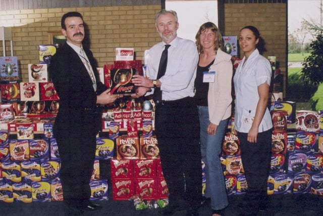 Howard Sharpe, service delivery manager of Adecco in Batley, presents the company's collected Easter eggs to Phil Clarke and Janet Hirst from the Westfield at Mirfield and Natalie Wood from Huddersfield Royal Infirmary's children's ward in 2005.