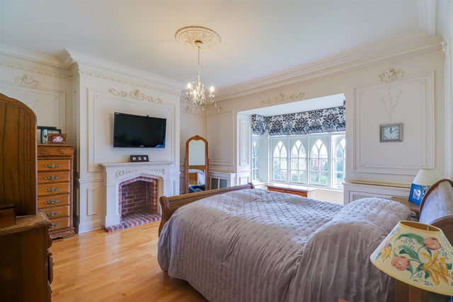 A decorative bedroom, with feature arched windows within the bay, and a fireplace.