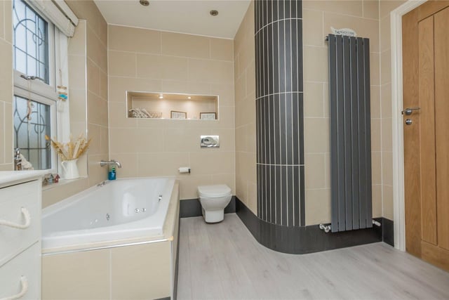 The stylish house bathroom, with a jacuzzi style air bath, engineered wood flooring, tiled walls and spotlights.