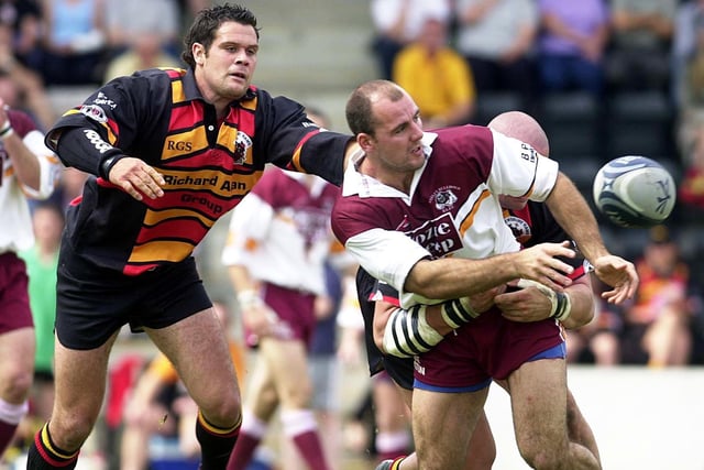 Batley Bulldogs' Andy Spink passes the ball despite being tackled in a derby clash in June 2003.