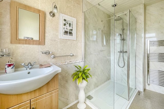 A walk-in shower, and wash basin within vanity unit feature in this tiled shower room.