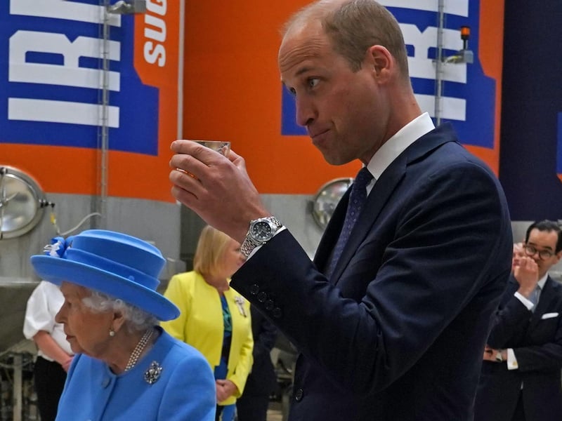 The Duke of Cambridge, known as the Earl of Strathearn in Scotland, tries Irn-Bru as Queen Elizabeth II looks on,.