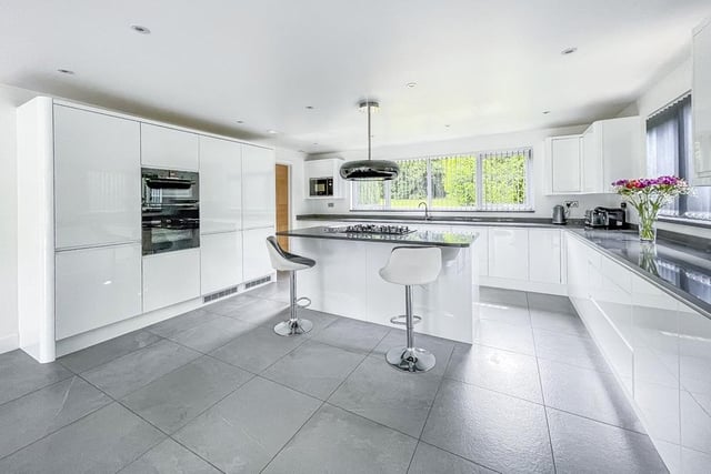 HIgh gloss units with granite work tops, and a central island are in this contemporary style kitchen.