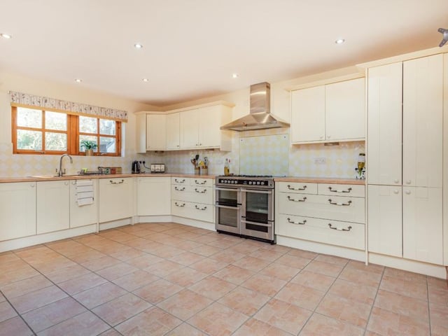 The kitchen features shaker-style cabinets, a full-size range cooker with hood, and ample room for a breakfast table.