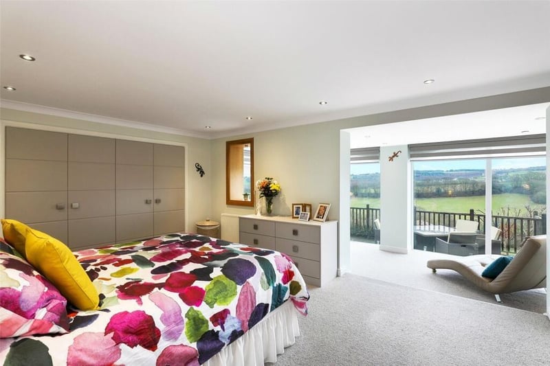 The primary bedroom has luxury walk-in wardrobes to one side and matching full wall fitted wardrobes opposite with downlighting to the ceiling and an opening to an adjacent sitting room.
