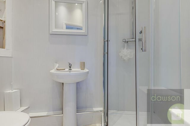 The shower room has a cubicle with mains waterfall shower, built-in shelving and spotlights.