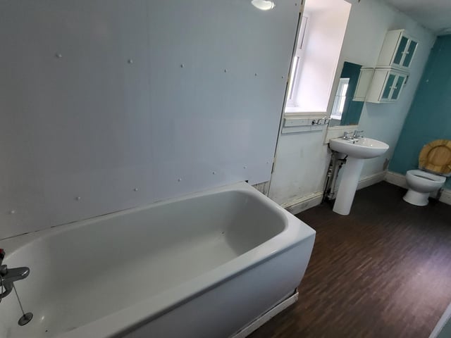 The bathroom has a white suite including bath and shower attachment.