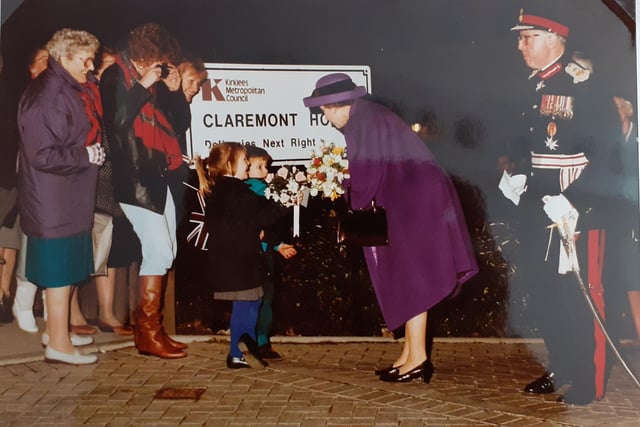 Queen Elizabeth II receiving flowers from two children.