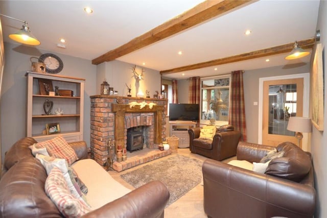 A beamed sitting room with rustic brick fireplace and cosy stove.